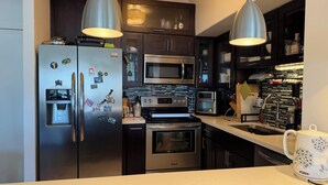 A modern kitchen with stainless steel appliances, including a refrigerator, microwave, and oven. - Cozy 1-bedroom condo 4miles from uc Berkeley with lots of public transportation (Emeryville)