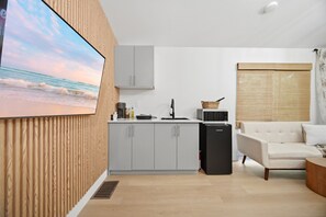 A modern kitchen with grey cabinets, a black refrigerator, and a small island with a sink.