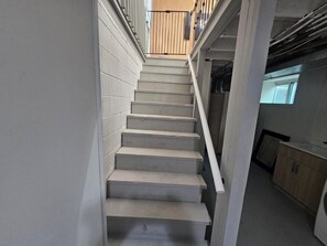 A concrete staircase with a metal handrail, leading to a wooden balcony.