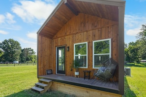 Eine Holzhütte mit Veranda, einer Tür und zwei Fenstern.