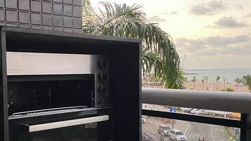 Een keuken met een inbouwoven en uitzicht op een drukke straat met palmbomen en een strand op de achtergrond.