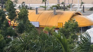 A beach with umbrellas and palm trees, a yellow building with a sign, and the ocean in the background. - Hotel Platinum Landscape Luxo apartment (Fortaleza)