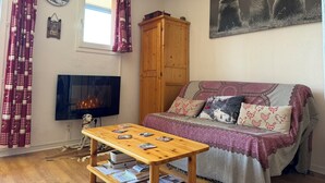 Ein gemütliches Wohnzimmer mit einer Couch, einem Holztisch, einem Kamin und einem Gemälde von Murmeltieren.