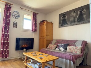 Ein gemütliches Wohnzimmer mit einer Couch, einem Holztisch, einem Kamin und einem Gemälde von Murmeltieren.