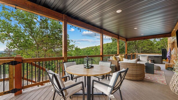A covered outdoor deck with a round table and chairs, a sofa, and a grill area. - Not So Crappie Cabin - 3BR/3BA, Private Hot Tub, Resort Pools & Lazy River (Hollister)