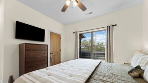A bedroom with a bed, a dresser, a television, and a window with curtains. - Not So Crappie Cabin - 3BR/3BA, Private Hot Tub, Resort Pools & Lazy River (Hollister)