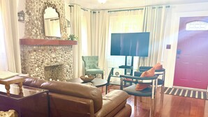 Ein Wohnzimmer mit Kamin aus Stein, einer Ledersofa, einem Fernseher und einer roter Tür.