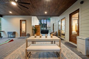 Un patio spazioso con tavolo e panche in legno, una vasca idromassaggio e vista su una zona boschiva.