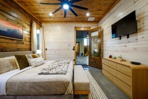 Een slaapkamer met een bed, nachtkastje en een aan de muur bevestigde televisie.
