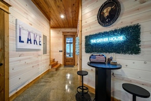 A wooden interior hallway with a sign reading 'Lake' and a neon sign for 'The Gather House'. - The Gather House | Private Pool • Sauna • Game Room • UTV Trail Access • Sleeps 26 (Broken Bow)