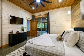 A bedroom with a bed, a TV, a dresser, and a large window. - The Gather House | Private Pool • Sauna • Game Room • UTV Trail Access • Sleeps 26 (Broken Bow)