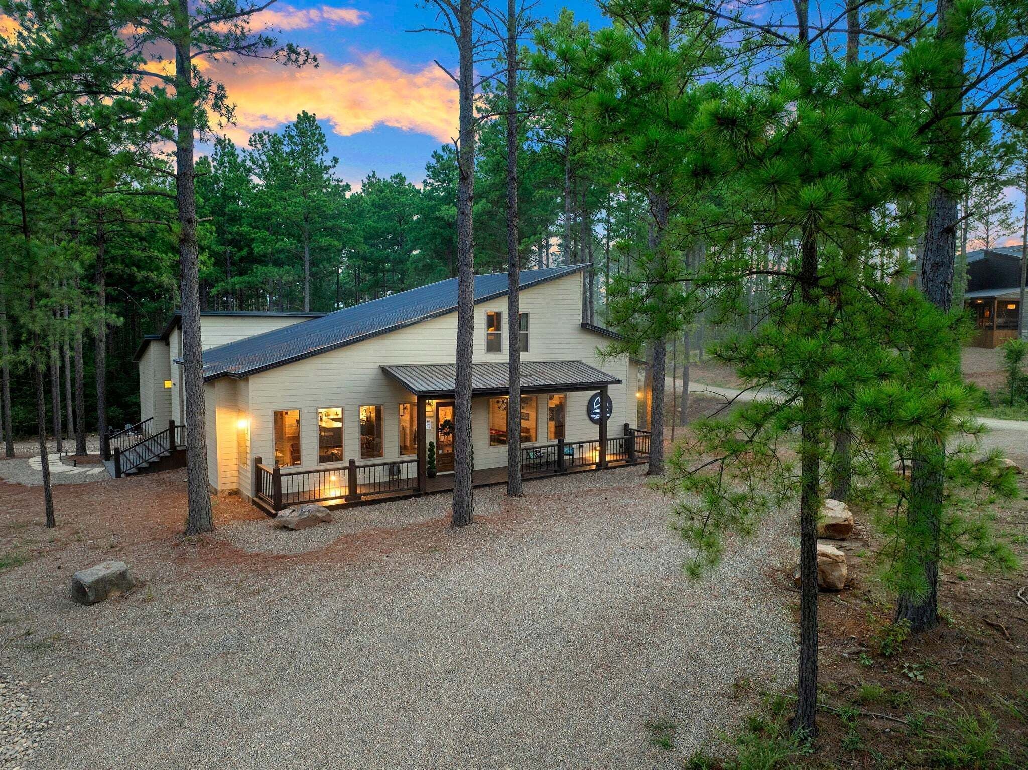A two-story building with a gravel driveway, surrounded by trees.