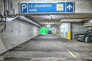 Eine Parkgarage mit Hinweisschildern, Betonwänden und einem Auto rechts.