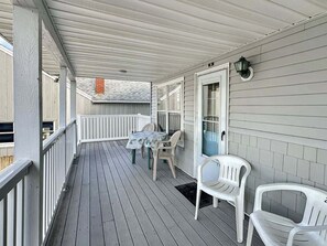A covered porch with a table and chairs, a door, and a small window. - Walk to Wells Beach | Cozy 1BR w/ Loft Condo (Wells)