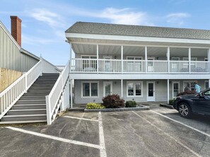 A two-story building with a covered porch and a staircase leading to the entrance. - Walk to Wells Beach | Cozy 1BR w/ Loft Condo (Wells)