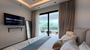 Una camera d'albergo con un letto, una TV a muro, un balcone con tavolo e sedie e vista sull'esterno.
