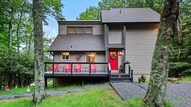 A two-story cabin with a deck, surrounded by trees. - Bearfoot Beech - Game table, fire pit, pets ok, hot tub! (Banner Elk)