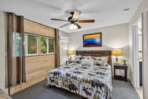 A bedroom with a bed, a ceiling fan, a window, and a painting on the wall. - Bearfoot Beech - Game table, fire pit, private hot tub! (Banner Elk)