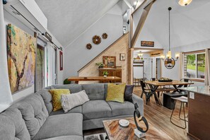 Ein modernes Interieur mit einem grauen Sofa, einem Holzesstisch und einer Küchenzeile.