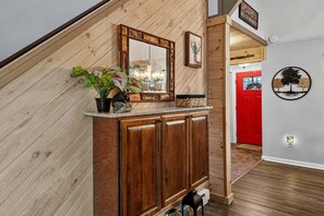 A wooden staircase with a mirror, a potted plant, and a red door leading to another room. - Bearfoot Beech - Game table, fire pit, private hot tub! (Banner Elk)