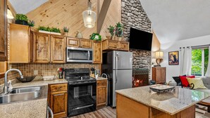 A kitchen with wooden cabinets, a stainless steel refrigerator, a microwave, and a stove. - Bearfoot Beech - Game table, fire pit, pets ok, hot tub! (Banner Elk)
