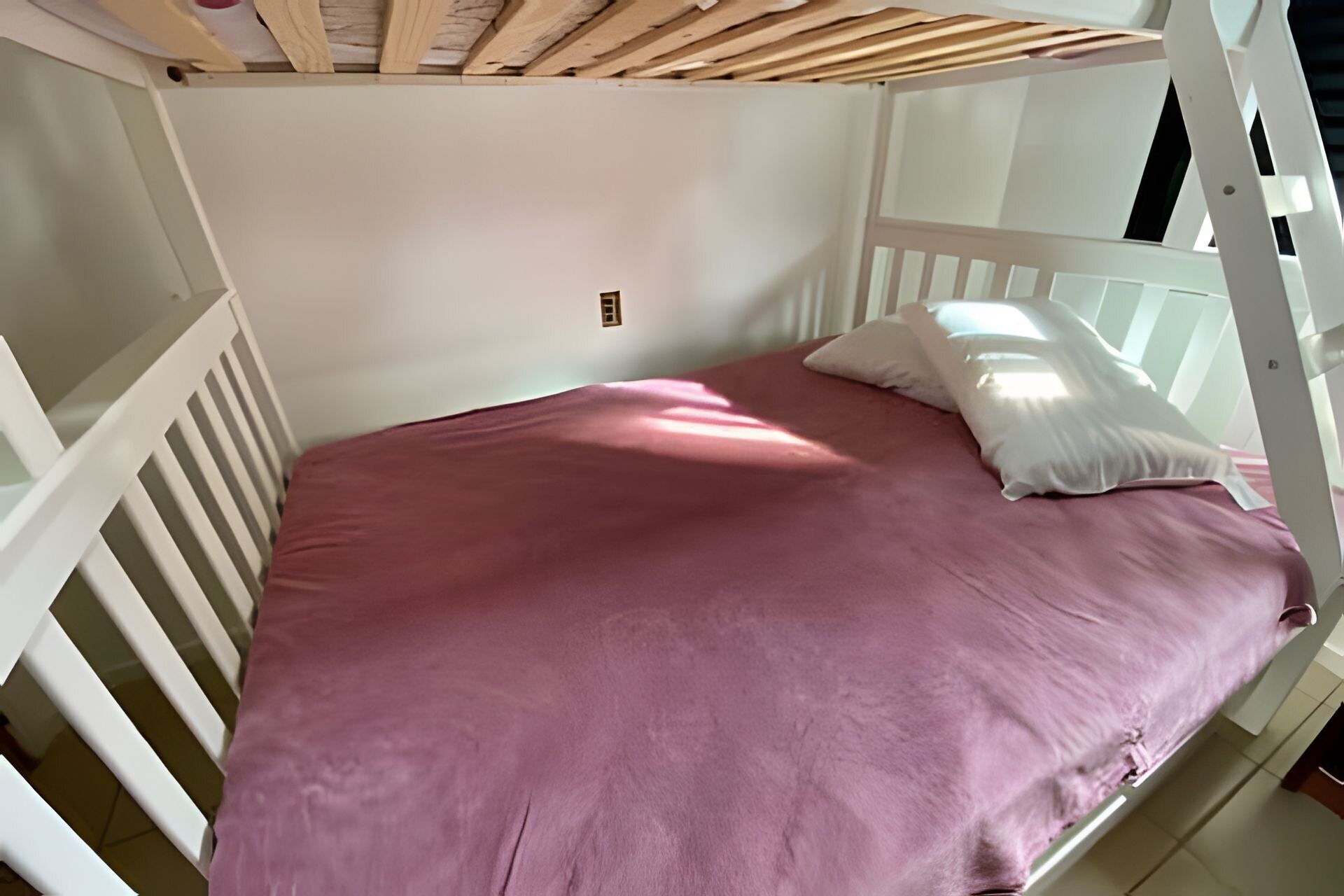 Ein Etagenbett mit rosa Matratze und weißen Geländern.