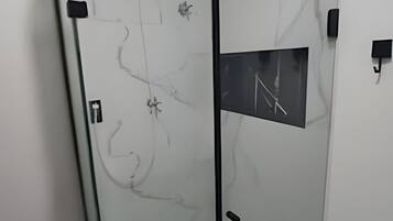 Une cloison en verre avec une petite fenêtre, une porte et un panneau de commande fixé au mur.