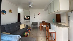 Un espacio habitable compacto con sofá, mesa de comedor y kitchenette.