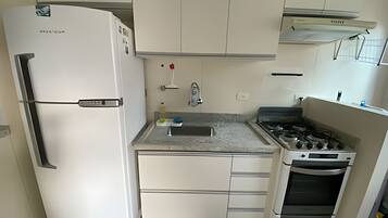 Una cocina compacta equipada con refrigerador, estufa, horno y una pequeña encimera.