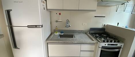 A compact kitchen with a refrigerator, stove, oven, and a small countertop.