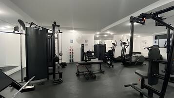A gym with various exercise equipment, including a squat rack, bench press, and treadmills.