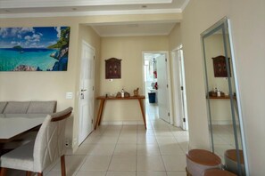 A hotel room with a dining area, a view of the sea, and a mirror. - Fully Furnished Apartment in the Heart of Pitangueiras, Spacious Apartment in Guarujá (Guarujá)