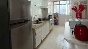 Een moderne keuken met een roestvrijstalen koelkast, een spoelbak en een rode waterkoker op het aanrecht.