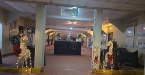 Un área de recepción interior con un mostrador, plantas en macetas y un árbol de Navidad.