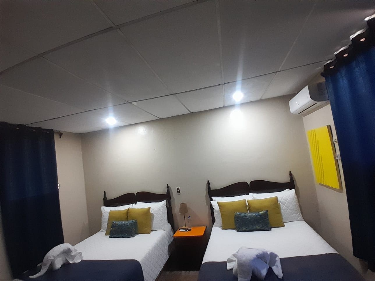 Une chambre d’hôtel avec deux lits, une table de chevet et un climatiseur fixé au mur.