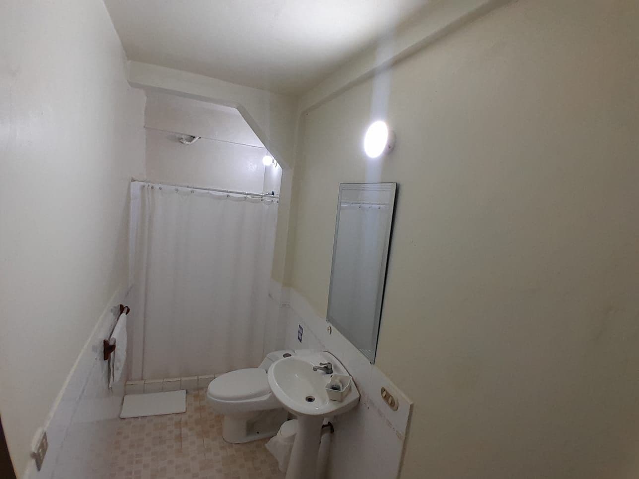 Un baño pequeño con inodoro, lavabo y ducha.