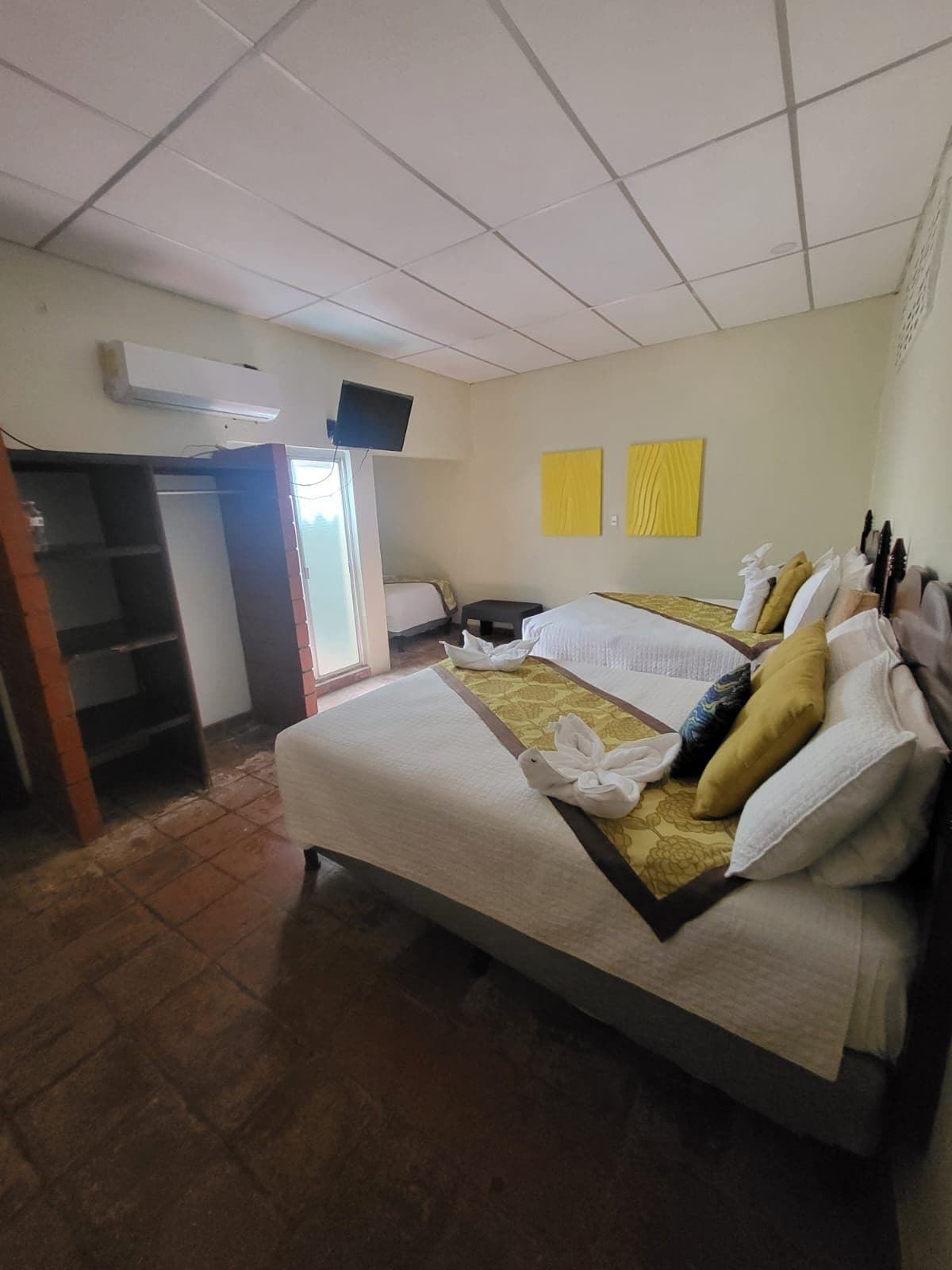 Une chambre d’hôtel avec un lit, une télévision, une armoire et une fenêtre.