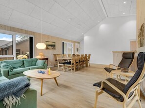 Ein geräumiger Wohnbereich mit einem grünen Sofa, einem Holzesstisch und einem schwarzen Ledersessel.