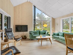 A spacious living room with a large window, a flat-screen TV, and a green sofa. - "Ylermi" - 600m from the sea by Interhome (Thisted)