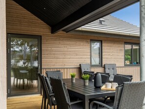 A modern outdoor dining area with a wooden deck, black chairs, and a glass table. - "Ylermi" - 600m from the sea by Interhome (Thisted)
