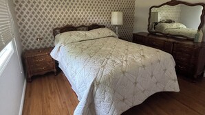 Un dormitorio con una cama grande, un aparador, una mesita de noche, una lámpara y un espejo.