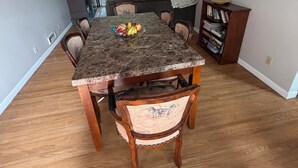 Un comedor con una mesa de mármol, sillas de madera, una lámpara de araña y una estantería.