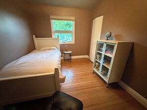 A bedroom with a bed, a nightstand, a window, and a cabinet. - Cozy home away from home in NW Calgary. Great location and has all amenities (Calgary)