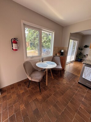 A kitchen with a dining area, a fire extinguisher mounted on the wall, and a large window. - Cozy home away from home in NW Calgary. Great location and has all amenities (Calgary)