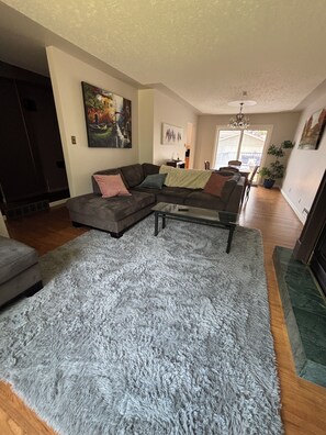 A living room with a sectional sofa, a coffee table, and a shaggy rug. - Cozy home away from home in NW Calgary. Great location and has all amenities (Calgary)