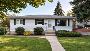 A single-story house with a front porch, a set of stairs leading to the entrance, and a well-maintained lawn. - Cozy home away from home in NW Calgary. Great location and has all amenities (Calgary)