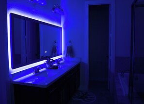 Ein Badezimmer mit großem Spiegel, Waschbecken und Handtuchhalter.