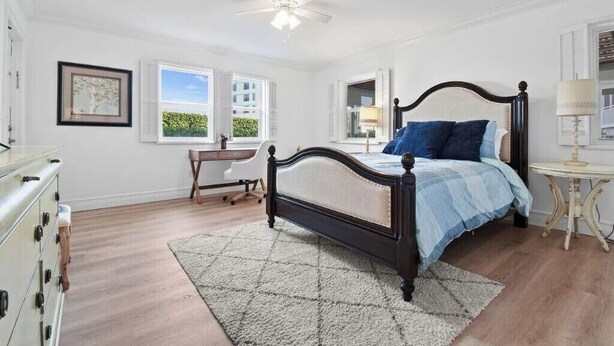 Un dormitorio con cama, cómoda, escritorio y ventanas.