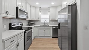 Una cocina moderna con armarios blancos, electrodomésticos de acero inoxidable y una isla central.