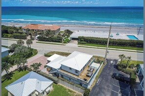 Ein Küstenanwesen mit Pool und Blick auf den Strand, eine Straße führt zum Strand.